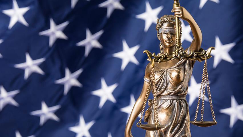 blindfolded goddess of justice against the flag of the United States of America